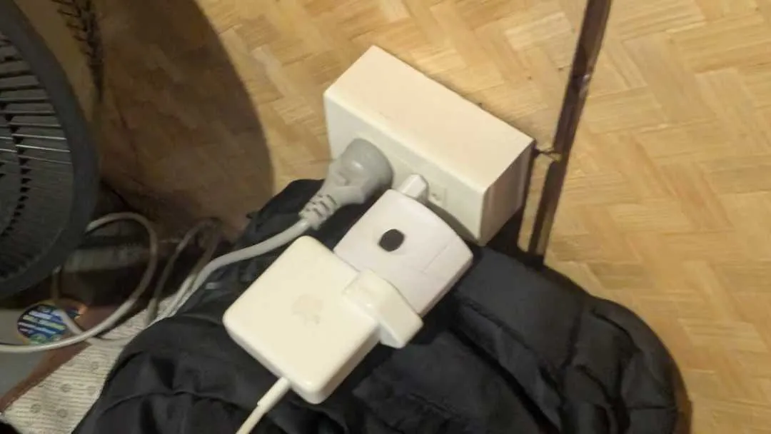 A plug in an adapter in a socket, all balancing on a bag