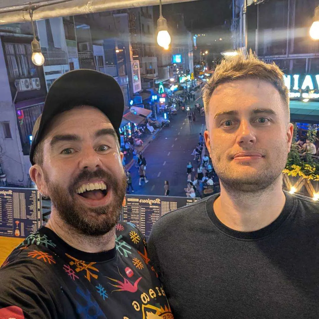 Two friends pose at a rooftop bar