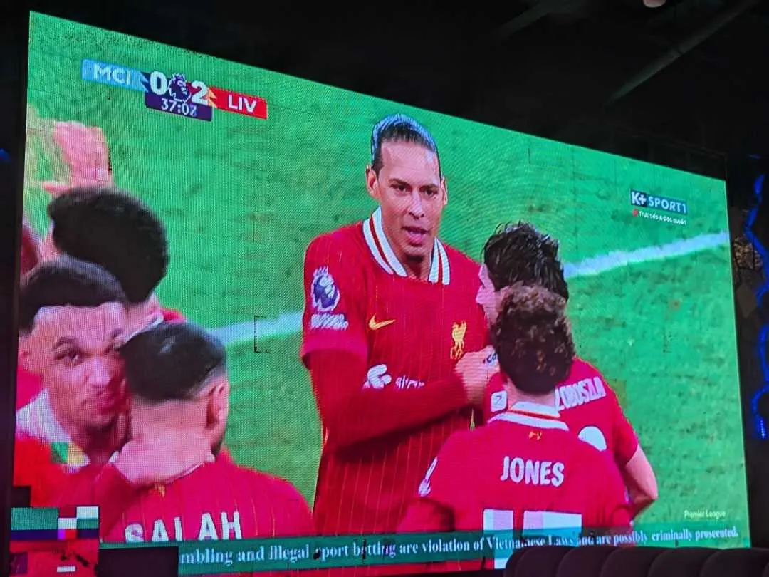 A screen showing Liverpool players celebrating after scoring a goal against Manchester City