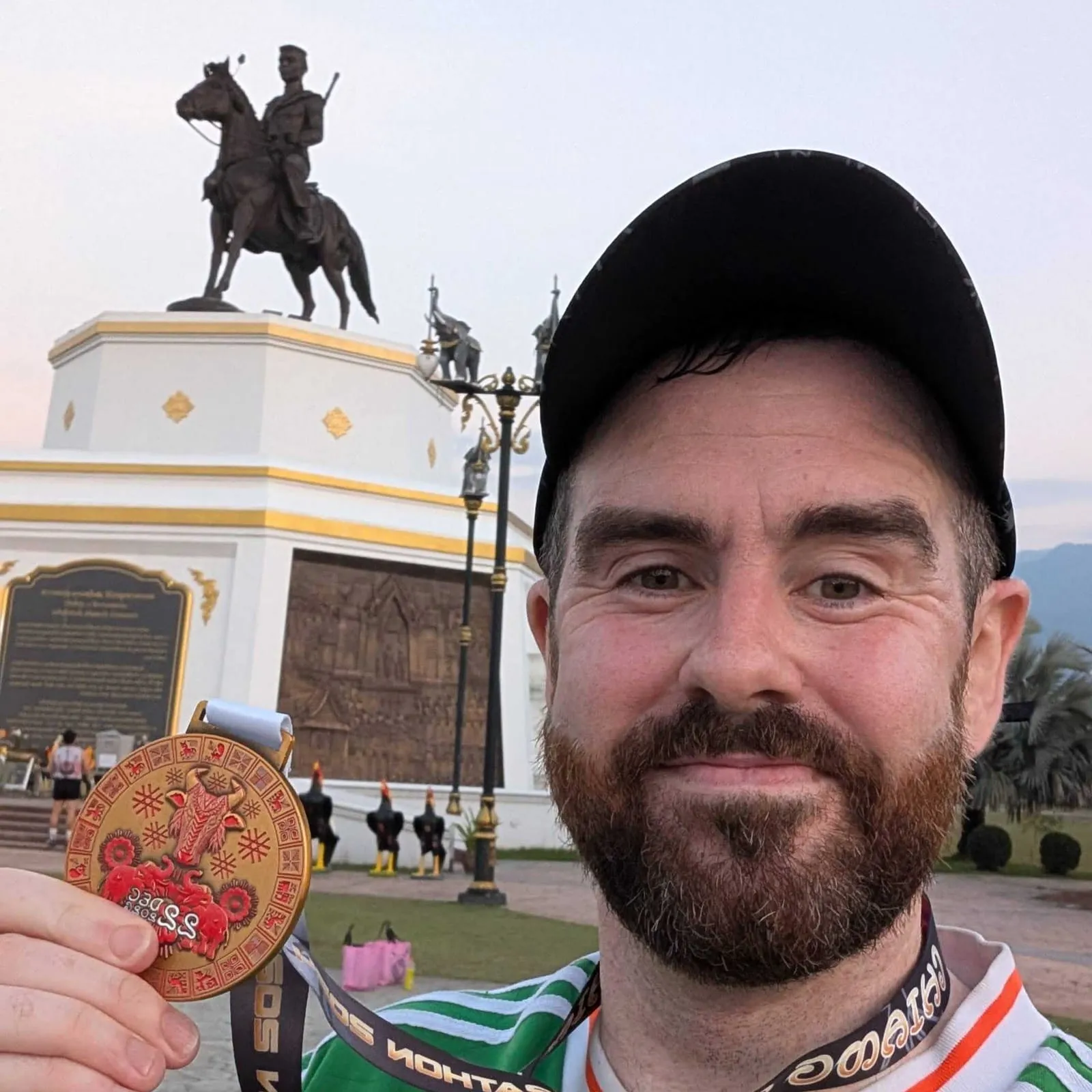 A young man showing off his medal with a statue behind him