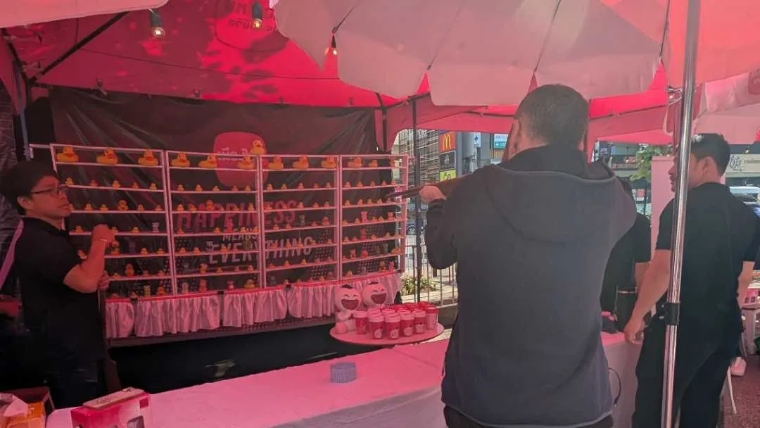 A man shooting an air rifle at some prizes in a tent