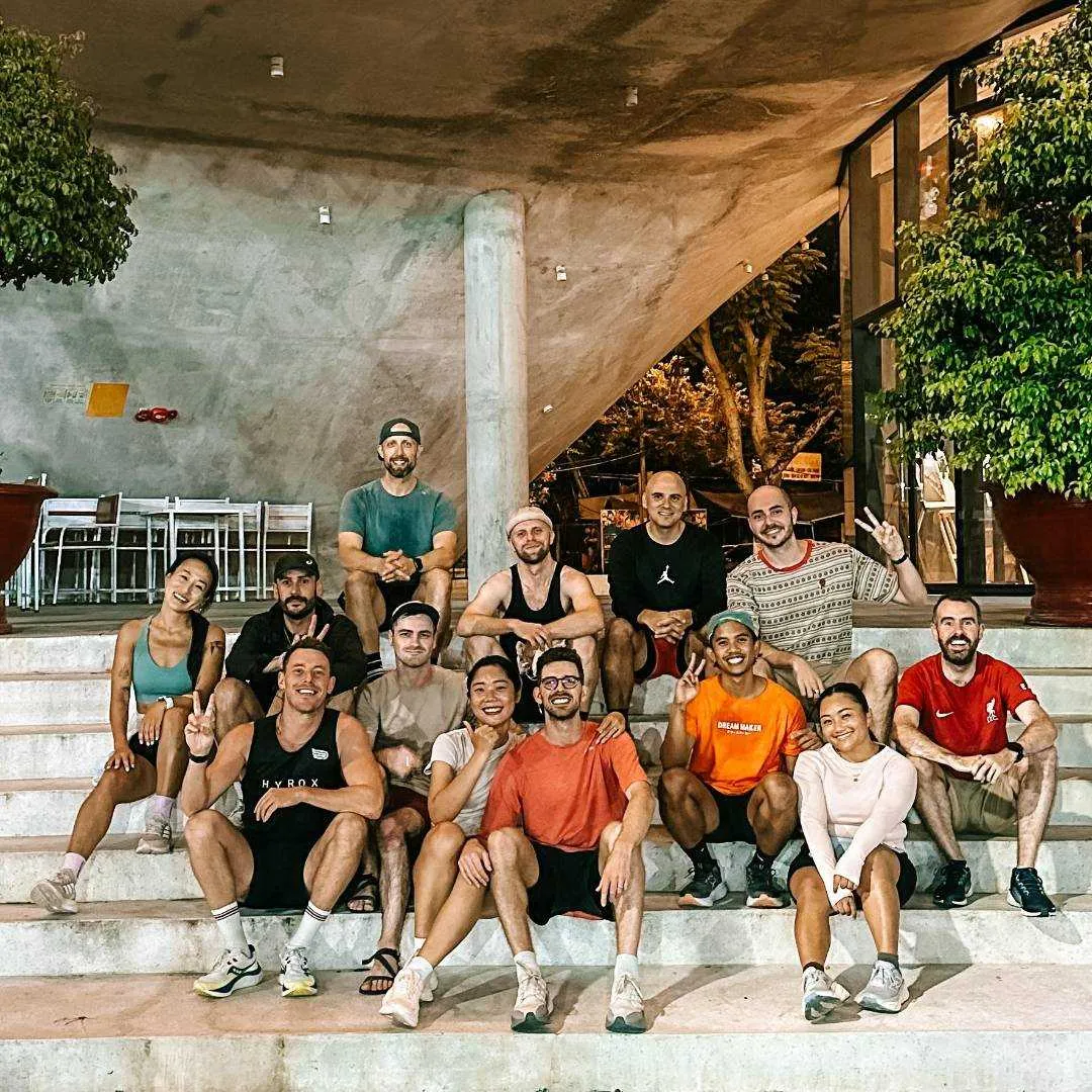 A smiling crowd of people sitting on some steps after they completed a running session