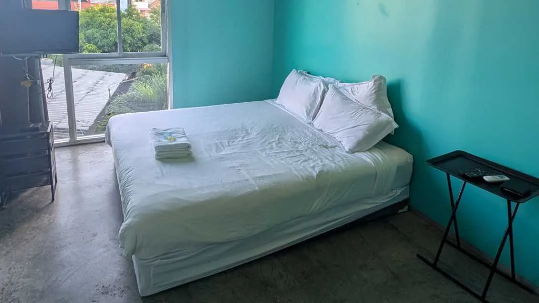 A guest house bed with a door to a balcony
