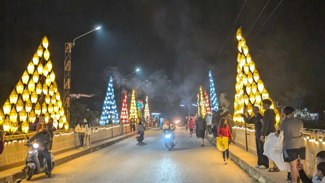 A small lit-up bridge at night time with people on it