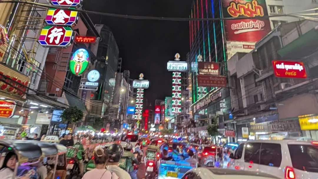 A busy Chinatown with traffic and advertising boards