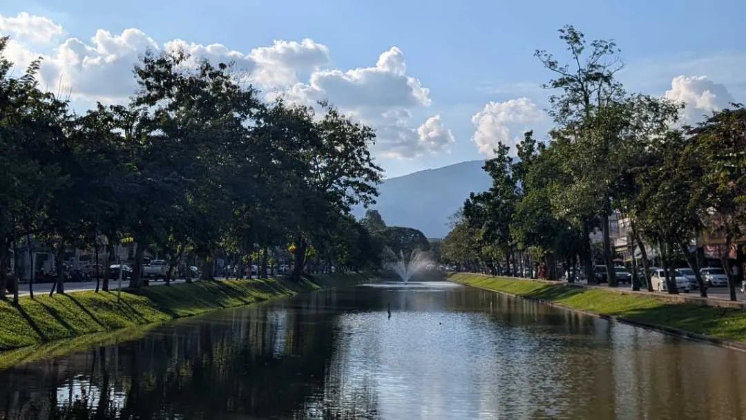 A moate with greenery on both sides and a mountain in the background