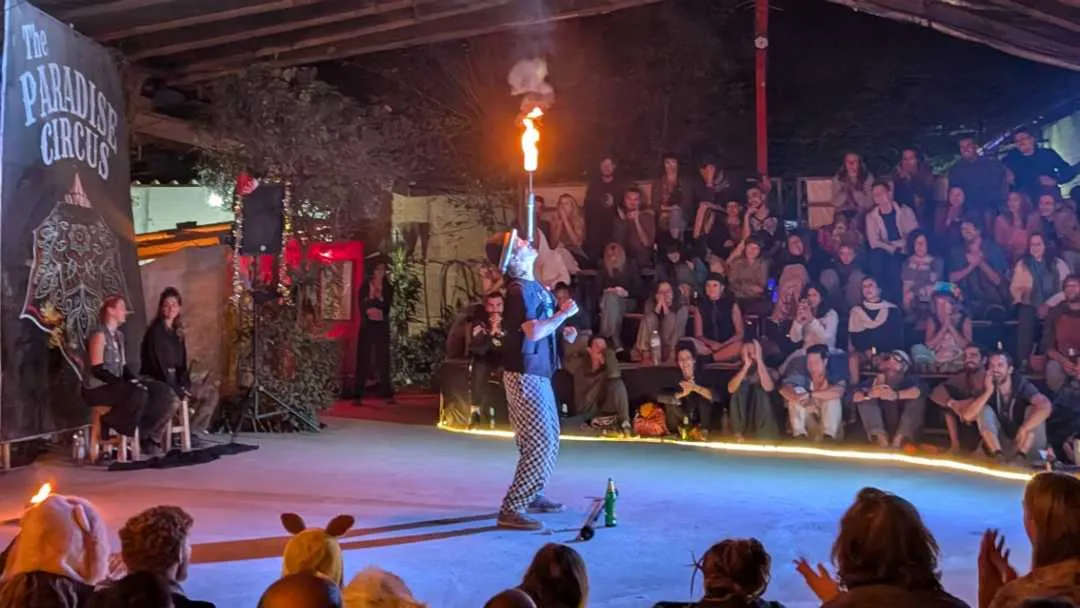 A circus performer balancing a flaming stick on his head