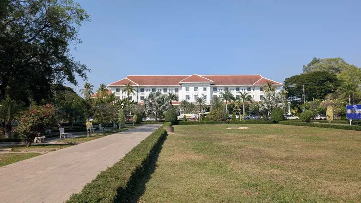 Picture of the Raffles Grand Hotel d'Angkor—a large white building with well kept gardens