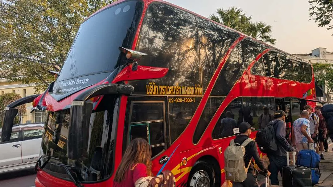 A big red bus with people about to embark