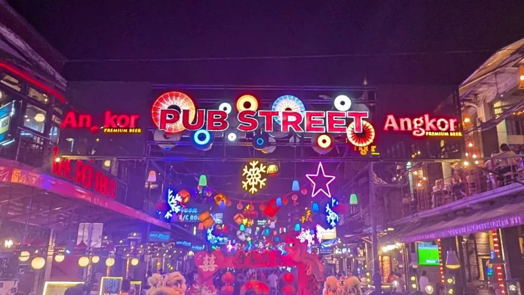 A busy street at night with bars and people about