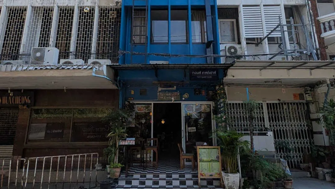 The outside of a blue cafe with buildings next to it