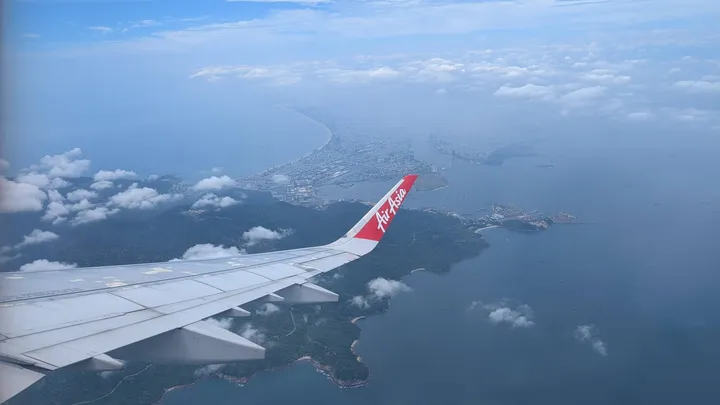A picture looking out the window of an aeroplane. The wing can be seen with Da Nang in the background