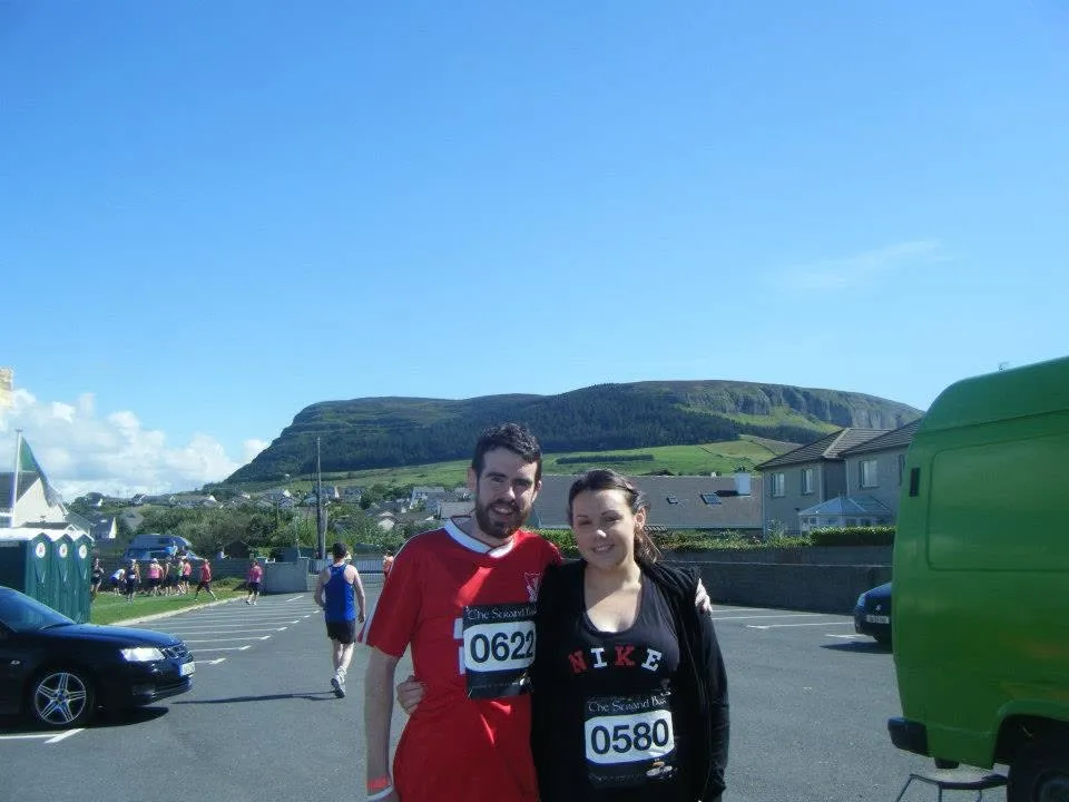 Two people posing for a photograph with a mountain in the background